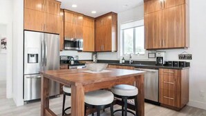 A modern kitchen with wooden cabinets, stainless steel appliances, and a central island with stools. - Spotless Modern Steps from the Best Shops and Restaurants. (Portland)
