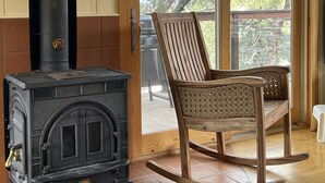 A room with a wood-burning stove, a rocking chair, and a sliding glass door leading to an outdoor area.