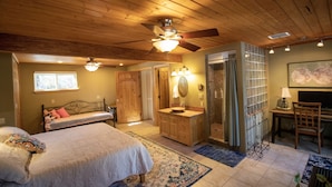 A bedroom with a bed, a vanity, a desk, and a chair.
