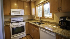 A kitchen with wooden cabinets, a white microwave, a stove, a dishwasher, and a coffee maker.