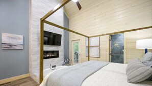 A bedroom with a large bed, a television mounted on the wall, and a fireplace. - Pet-Friendly Cabin 5 minutes from town with stunning decor and views! (Broken Bow)