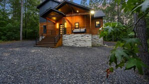 A cabin with a stone foundation, wooden exterior, and a porch with a bench. - Pet-Friendly Cabin 5 minutes from town with stunning decor and views! (Broken Bow)