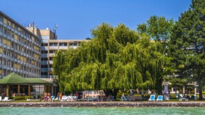 A waterfront hotel with a poolside area, a gazebo, and a large weeping willow tree. - Club Tihany Resort (Tihany)
