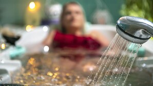 A bathtub with running water, a person in a red garment, and a blurred background with lights. - Club Tihany Resort (Tihany)