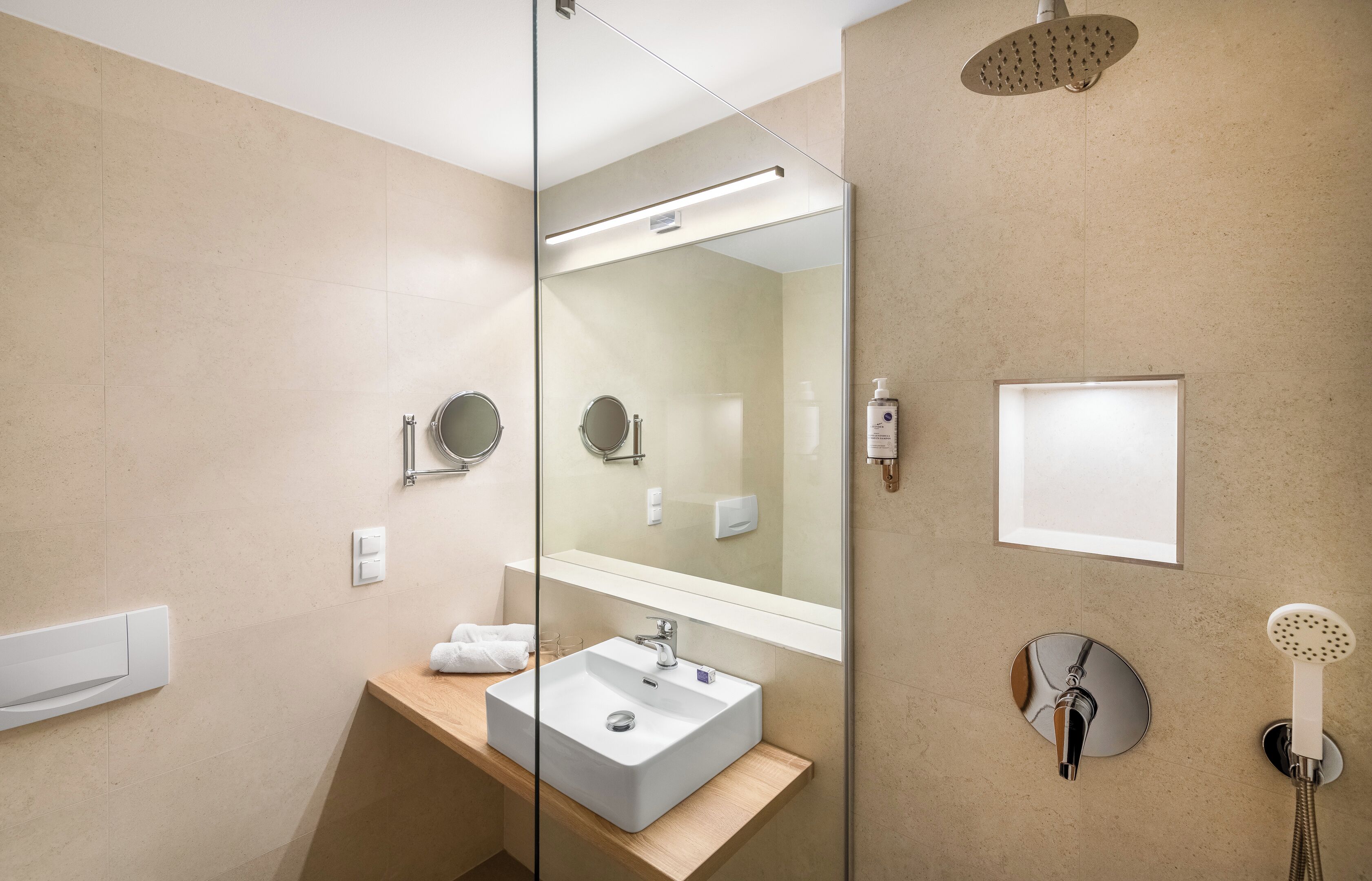 Une salle de bain moderne avec un grand miroir, un lavabo, une pomme de douche et un porte-serviettes.