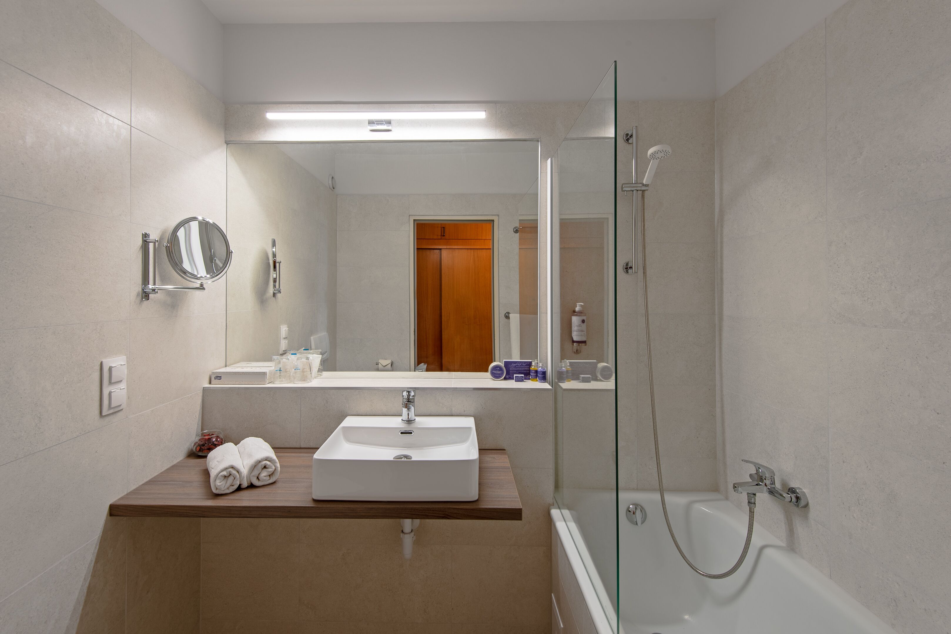 A modern bathroom with a sink, mirror, and glass-enclosed shower.