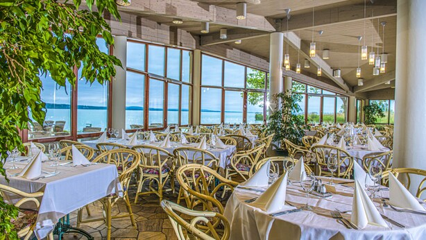 A restaurant with tables set for dining, large windows, and a view of the water. - Club Tihany Resort (Tihany)