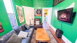 A cozy living room with a green wall, a leather sofa, a wooden coffee table, and a flat-screen TV. - ITH CoLive Little Italy (San Diego)