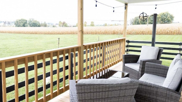 Een overdekt terras met rieten meubilair en uitzicht op een veld.