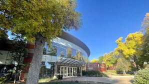 A modern building with a glass facade, surrounded by trees and greenery. - Walk Everywhere - Art, Restaurants, Poudre River (Fort Collins)