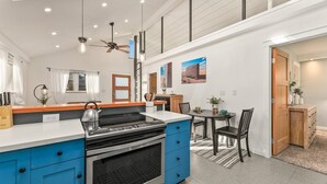 A modern kitchen with blue cabinets, a gas stove, and a ceiling fan. - Vibrant Downtown Bungalow – Walk Everywhere! (Fort Collins)