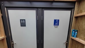 Un conjunto de puertas dobles con un cartel de baño y un icono de inodoro.