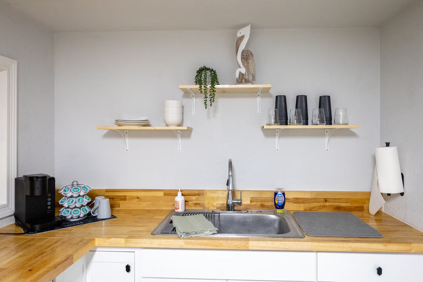 Eine Küche mit einer Holz Arbeitsplatte, einem Spülbecken und zwei Regalen darüber.