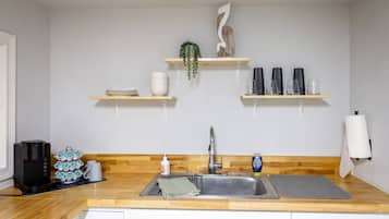 Eine Küche mit einer Holz Arbeitsplatte, einem Spülbecken und zwei Regalen darüber.