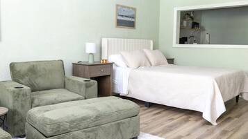 A bedroom with a bed, a nightstand, a lamp, a chair, and a small table.