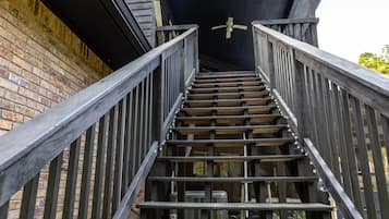 Un escalier en bois avec des rampes en métal menant à un plafond sombre.