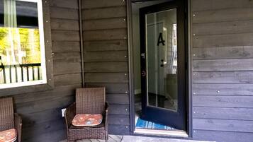 A wooden exterior with a glass door marked with the letter 'A' and two wicker chairs outside.