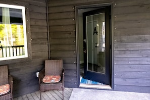 A wooden exterior with a glass door marked with the letter 'A' and two wicker chairs outside.