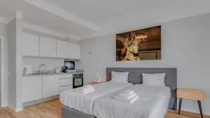 A modern hotel room with a large bed, a small kitchen area, and a painting on the wall. - Villa Winter (Funchal)