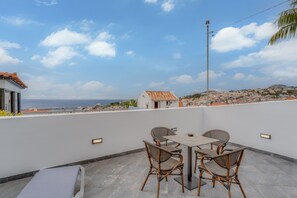 Terraza en la azotea con mesa y sillas, con vistas a un pueblo costero.