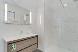 Panorama appartement | Badkamer | Een douche, een regendouche, een haardroger, een bidet