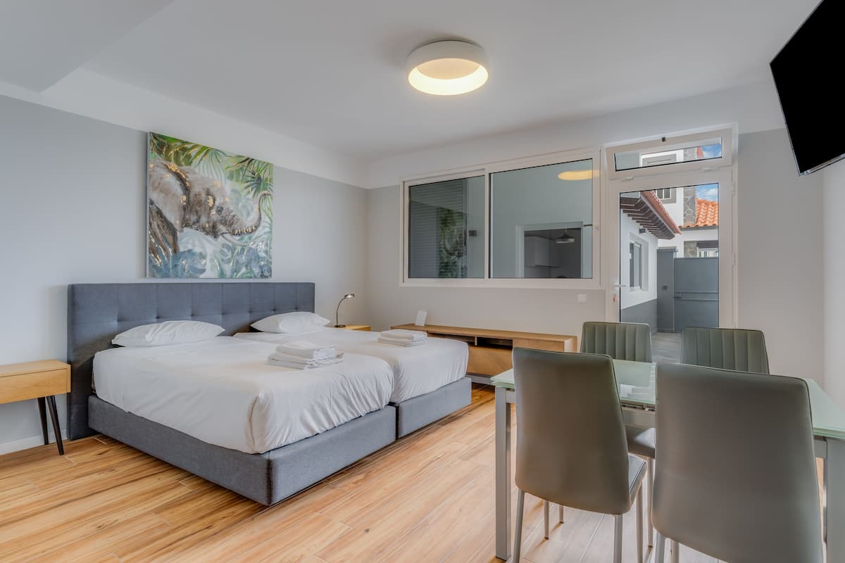 A modern hotel room with a large bed, a desk, and a dining area.