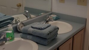 Un baño con dos lavamanos, un espejo y un perchero para toallas.