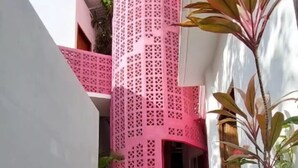 Een trap die leidt naar een gebouw met een roze gevel en een witte muur aan de linkerkant.