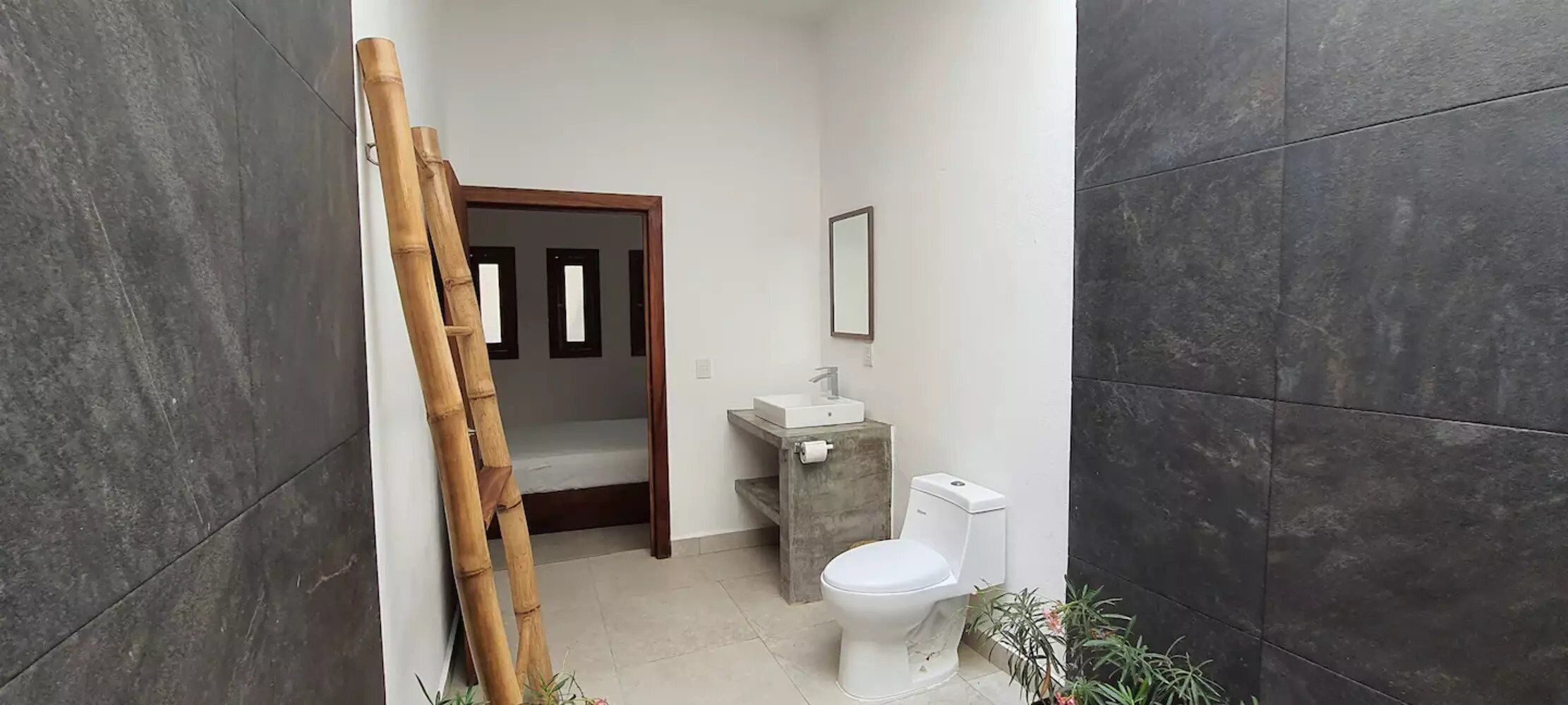 A bathroom with a toilet, sink, and a mirror on the wall.