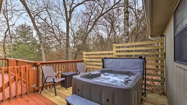 Ein Whirlpool auf einer Holzterrasse mit Stühlen und einem Holenzaun.