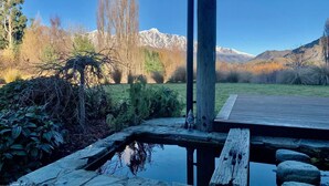 A wooden deck overlooking a pond with a mountain backdrop. - Mountain View Villa - Rural Retreat (Hot Tub, Tennis, Petanque, Putting Green) (Queenstown)