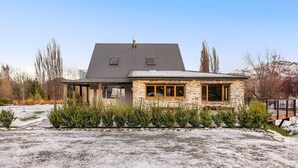 A two-story house with a stone facade and a large, dark roof. - Mountain View Villa - Rural Retreat (Hot Tub, Tennis, Petanque, Putting Green) (Queenstown)