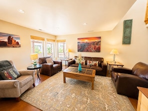A living room with leather sofas, a coffee table, patterned rug, and artwork on the walls.
