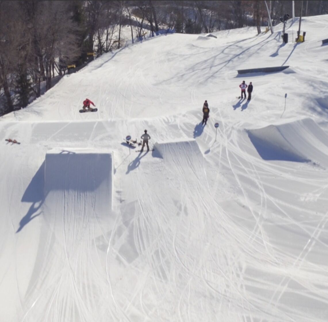 Une piste de ski enneigée où l’on voit plusieurs skieurs et snowboardeurs.