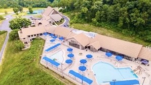 Um resort com uma piscina grande, várias áreas de descanso e um edifício com telhado curvo.