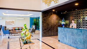 A modern reception area with a marble reception desk, a seating area with sofas and a coffee table, and a decorative sculpture. - The Star Hill  (Chiang Mai)