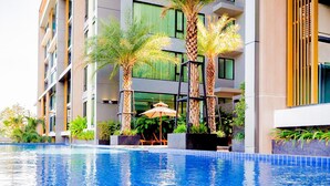 A modern hotel with a swimming pool, palm trees, and outdoor seating. - The Star Hill  (Chiang Mai)