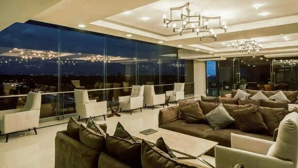 A modern lounge area with a high ceiling, large windows offering a city view, and contemporary furniture. - The Star Hill  (Chiang Mai)