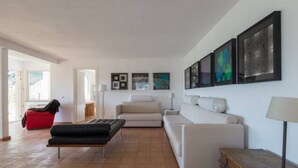 Ein modernes Wohnzimmer mit einer Couch, einem roten Sessel, einem Couchtisch und Kunstwerken an der Wand.