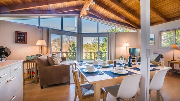 Una habitación acogedora con una mesa de comedor preparada para cuatro personas, un sofá y un televisor.