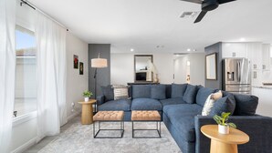 Una sala de estar moderna con un sofá modular, otomanas, una mesita auxiliar y un ventilador de techo.