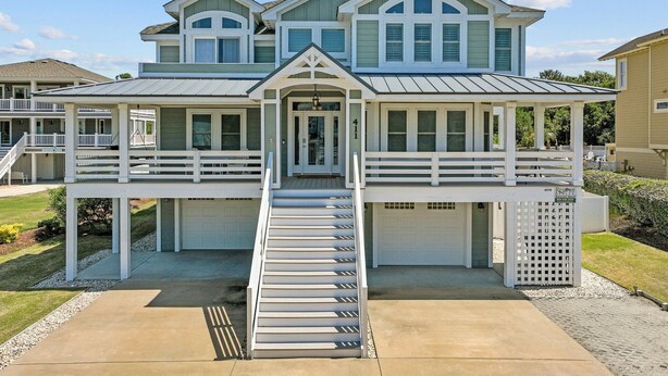 A two-story house with a covered front porch and a staircase leading to the garage. - 4919-The Leonardo - Soundside Oasis | Pool, Hot Tub & Fire Pit (Kitty Hawk)