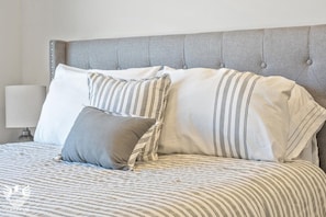 A bed with striped bedding and a tufted headboard.