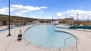 A swimming pool with a curved edge, surrounded by lounge chairs and a small bridge. - Ideal Family Getaway- Pickleball, Pool & Near Zion (Washington)