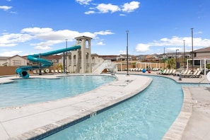 A swimming pool with a water slide, lounge chairs, and a tower structure.