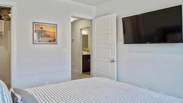 Ein Schlafzimmer mit Bett, Fernseher, Kleiderschrank und einer Tür zu einem anderen Raum.