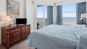 Una habitación de hotel con cama, cómoda, televisor y un cuadro.