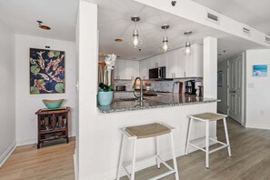 A modern kitchen with white cabinets, a granite countertop, and pendant lighting.