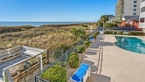 A beachfront property with a pool, a wooden deck, and a view of the ocean. - Stunning views, stylish oceanfront condo close to nightlife, shopping, dining and more! (North Myrtle Beach)