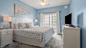 A bedroom with a bed, nightstands, a TV, a painting, and a window with curtains. - Spacious 5 bedroom oceanview condo - Cherry Grove Beach (North Myrtle Beach)